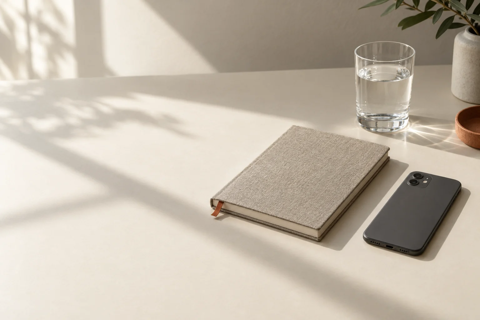 Illustrative still life of a closed notebook and a phone placed screen-down